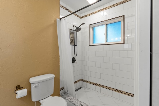 bathroom featuring a textured wall, tiled shower, and toilet