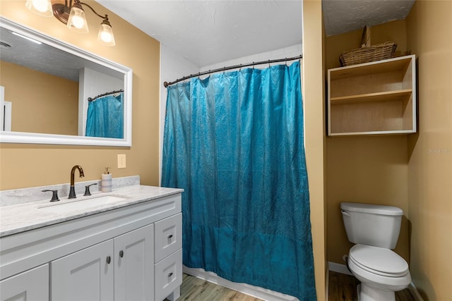 full bath featuring a textured ceiling, toilet, wood finished floors, vanity, and baseboards