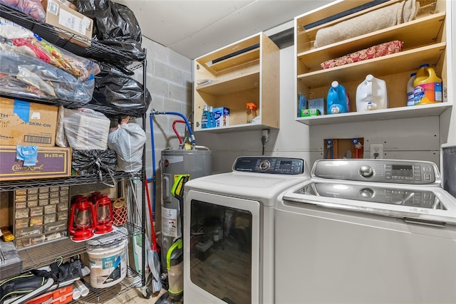 clothes washing area with concrete block wall, laundry area, electric water heater, and washer and clothes dryer