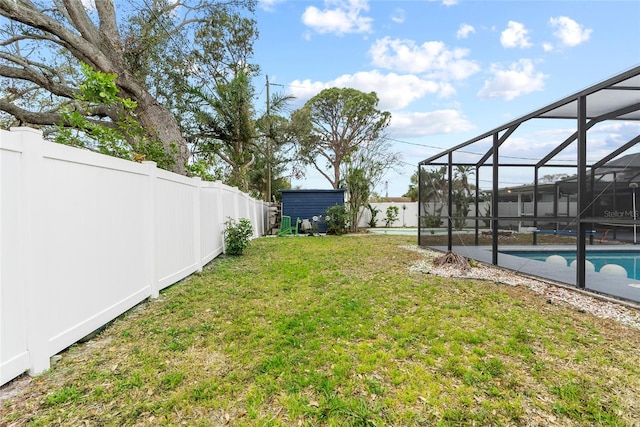 view of yard featuring a lanai, a storage shed, a fenced backyard, and an outdoor structure