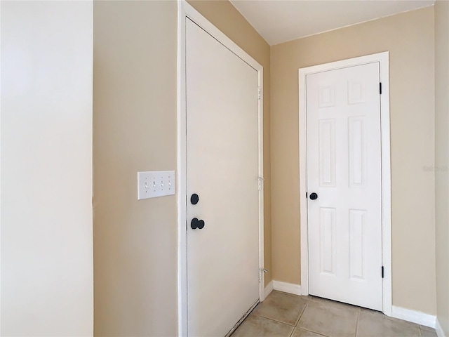 doorway with light tile patterned floors and baseboards