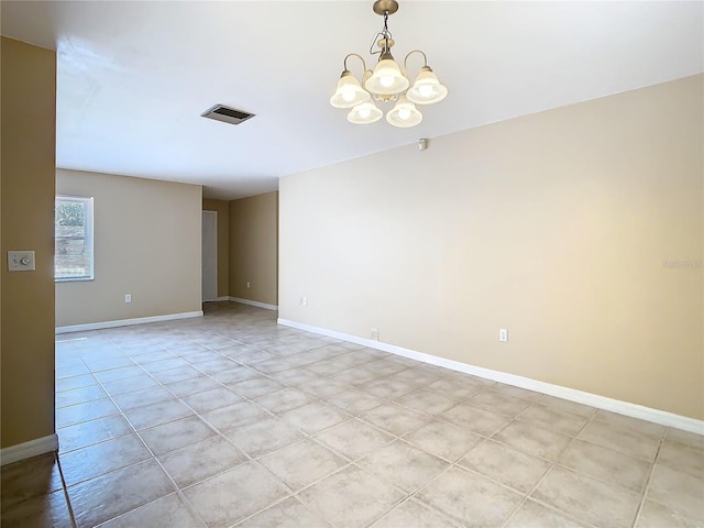 spare room featuring a chandelier, visible vents, and baseboards