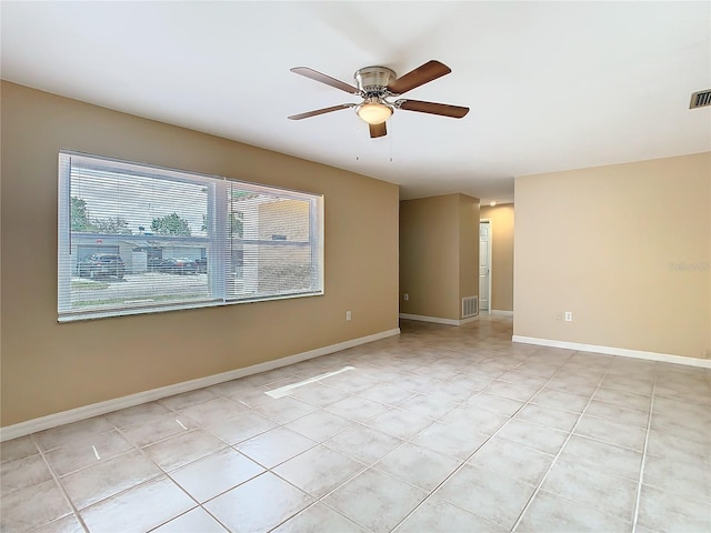 empty room featuring a ceiling fan, visible vents, and baseboards