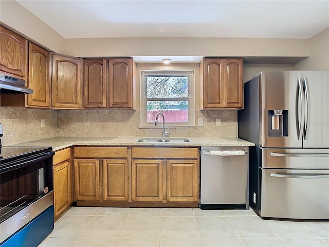 kitchen featuring appliances with stainless steel finishes, brown cabinetry, and a sink