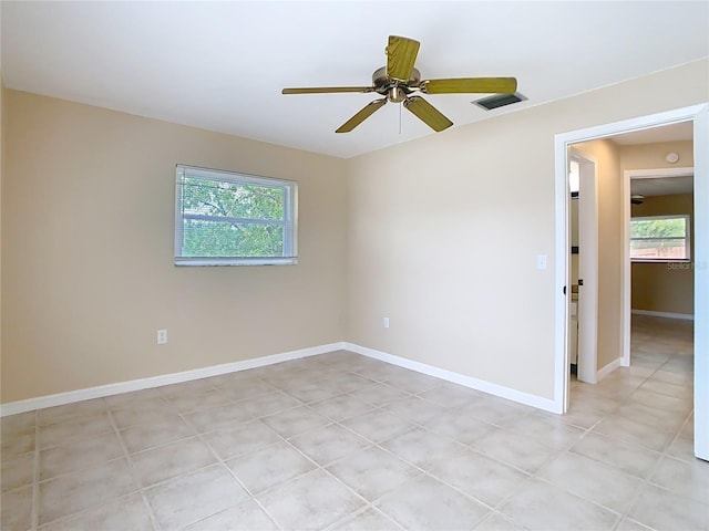 empty room with light tile patterned floors, baseboards, visible vents, and a ceiling fan