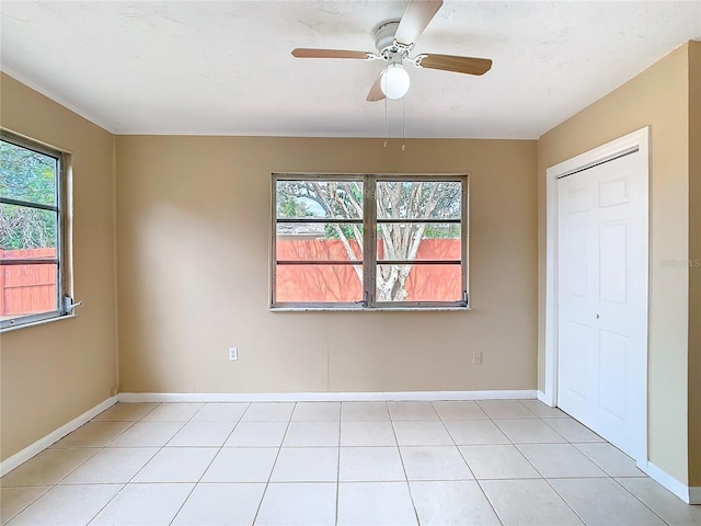 unfurnished room with a ceiling fan, baseboards, and light tile patterned floors