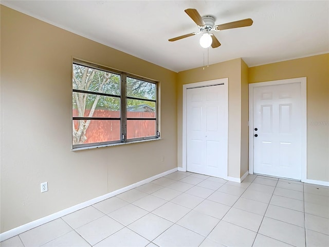 unfurnished bedroom with a ceiling fan, a closet, light tile patterned flooring, and baseboards