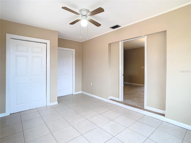 unfurnished bedroom featuring light tile patterned floors, a ceiling fan, visible vents, baseboards, and ornamental molding