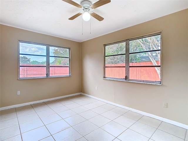 spare room with a ceiling fan, light tile patterned flooring, and baseboards