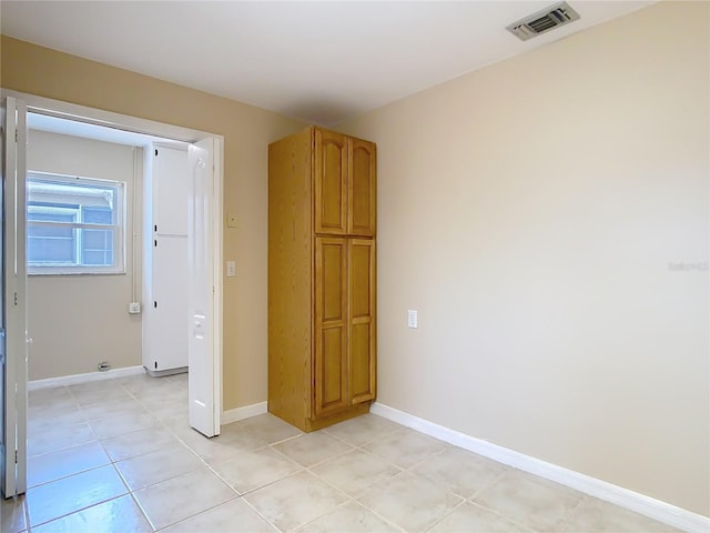 empty room with baseboards, visible vents, and light tile patterned flooring