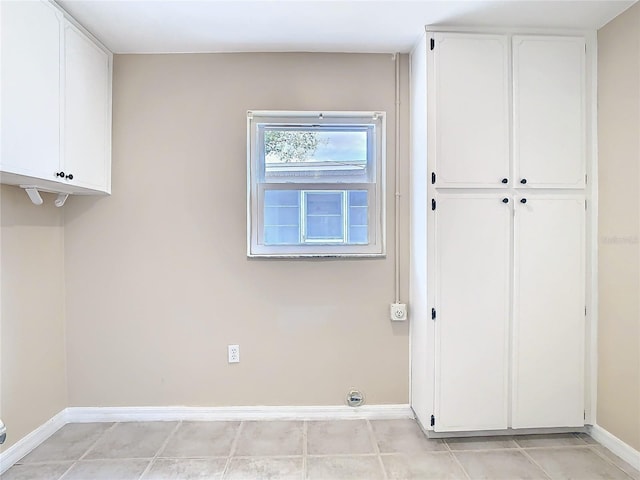 laundry room featuring cabinet space, baseboards, and light tile patterned floors