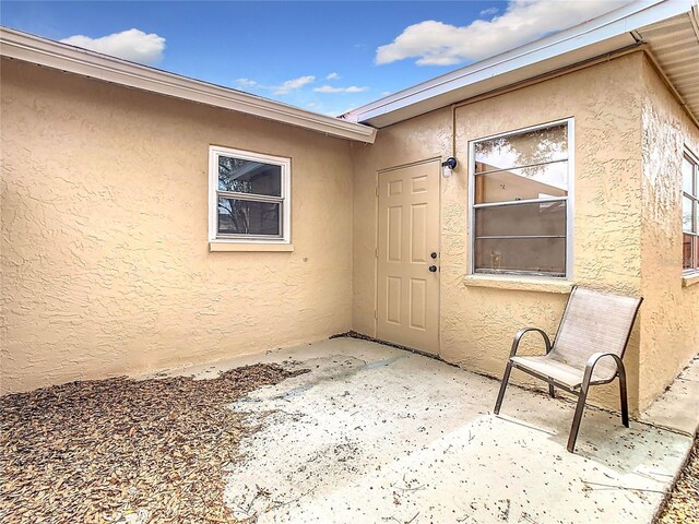 view of exterior entry featuring a patio and stucco siding