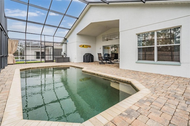 outdoor pool featuring ceiling fan, a patio, and glass enclosure