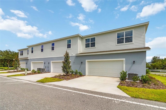 multi unit property with a garage, concrete driveway, stucco siding, and central air condition unit