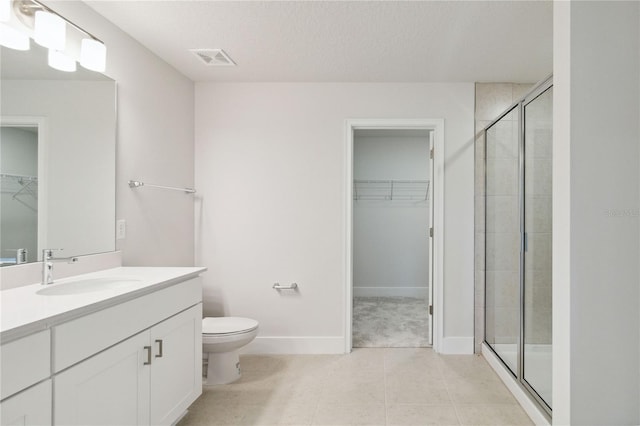 bathroom featuring visible vents, a spacious closet, toilet, a shower stall, and vanity