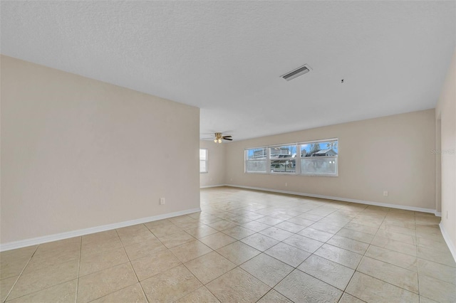 empty room with light tile patterned floors, baseboards, visible vents, ceiling fan, and a textured ceiling