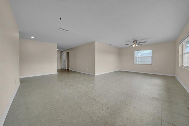 spare room featuring light tile patterned floors, a ceiling fan, and baseboards