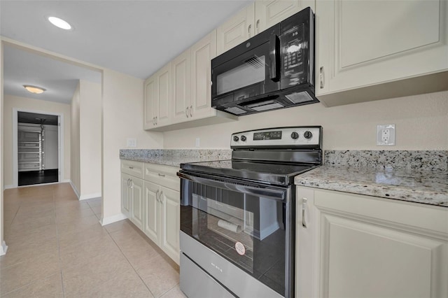 kitchen featuring baseboards, black microwave, light tile patterned floors, light stone counters, and stainless steel electric range