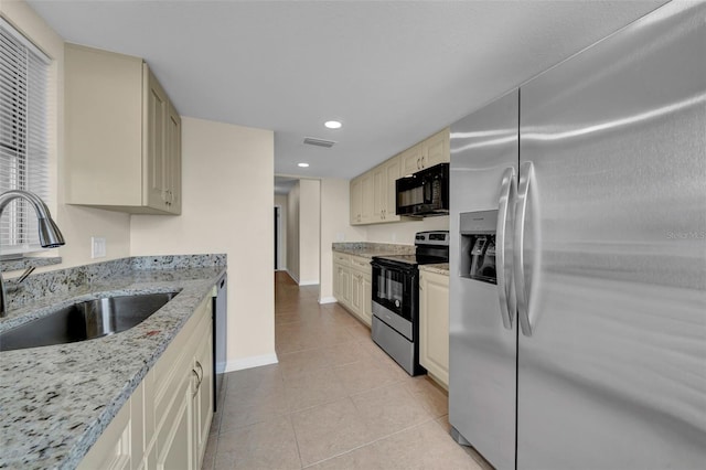 kitchen with electric range, a sink, cream cabinetry, stainless steel refrigerator with ice dispenser, and black microwave