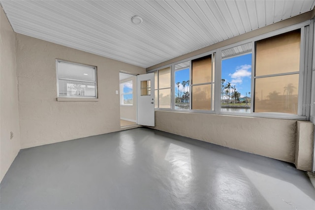 unfurnished room with finished concrete floors and a textured wall