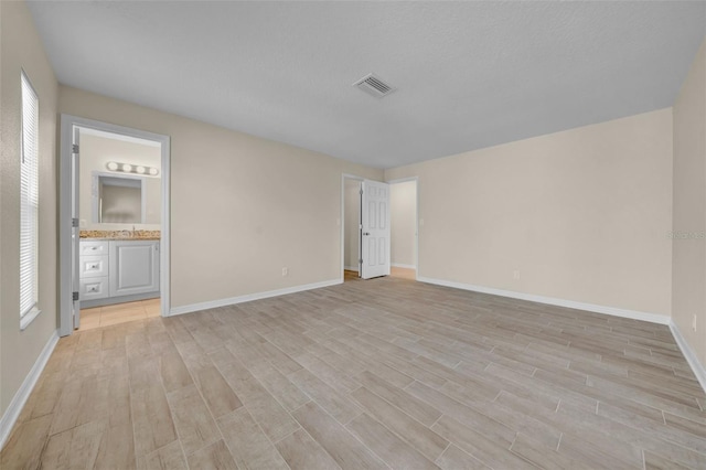 empty room featuring light wood finished floors, visible vents, and baseboards