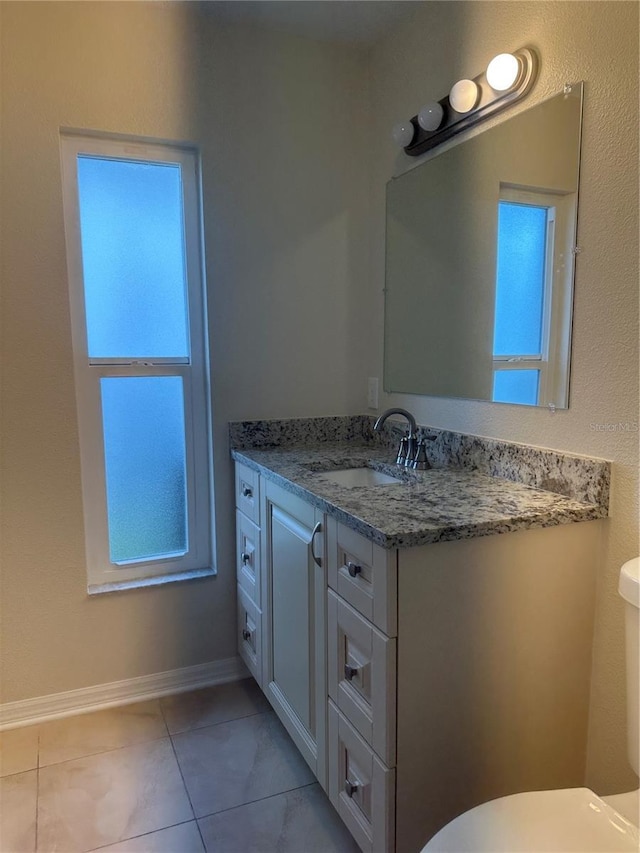 half bath with tile patterned floors, toilet, vanity, and baseboards