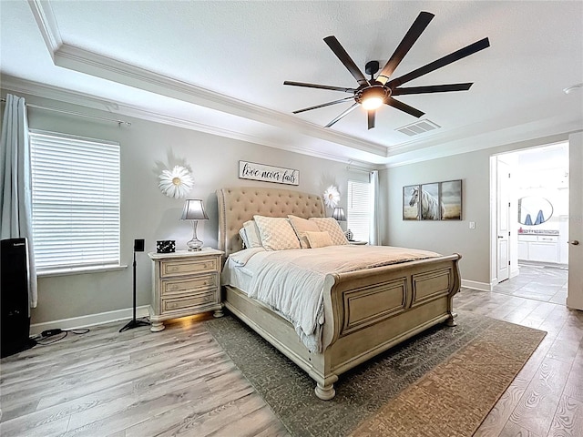 bedroom featuring crown molding, a raised ceiling, visible vents, light wood-style flooring, and baseboards