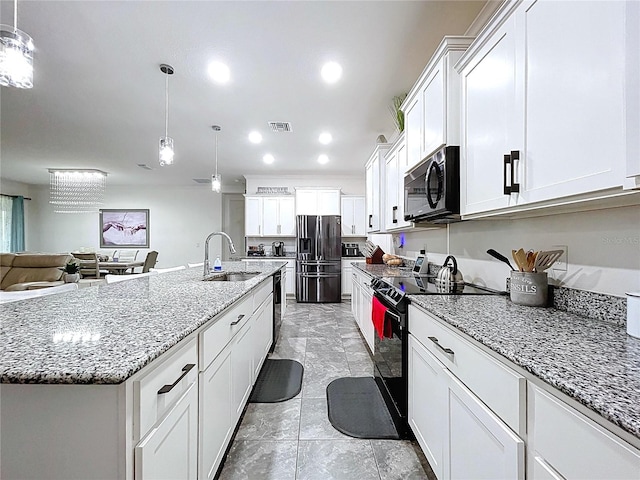 kitchen featuring hanging light fixtures, a kitchen island with sink, black appliances, white cabinetry, and a sink