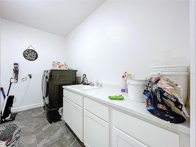 washroom with cabinet space, a sink, washer and clothes dryer, and baseboards