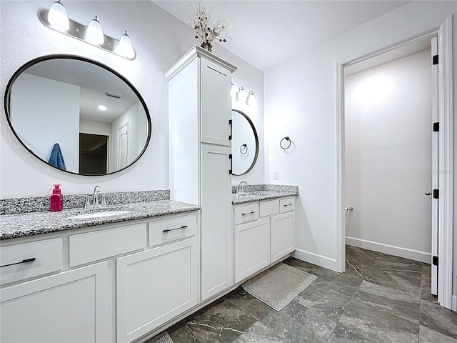 bathroom featuring baseboards, visible vents, two vanities, and a sink