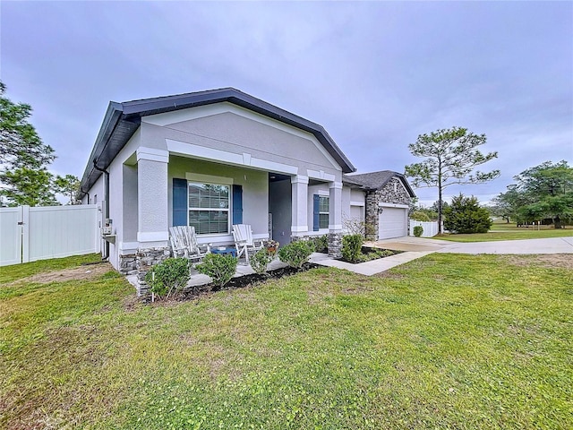 view of front of house with a porch, a garage, fence, stucco siding, and a front yard