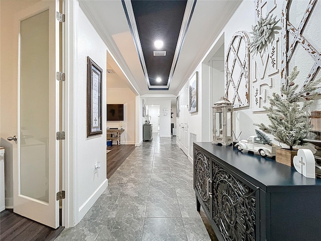 corridor with baseboards, a raised ceiling, visible vents, and crown molding