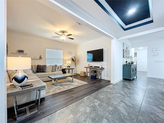 living area with ceiling fan, a textured ceiling, visible vents, baseboards, and ornamental molding