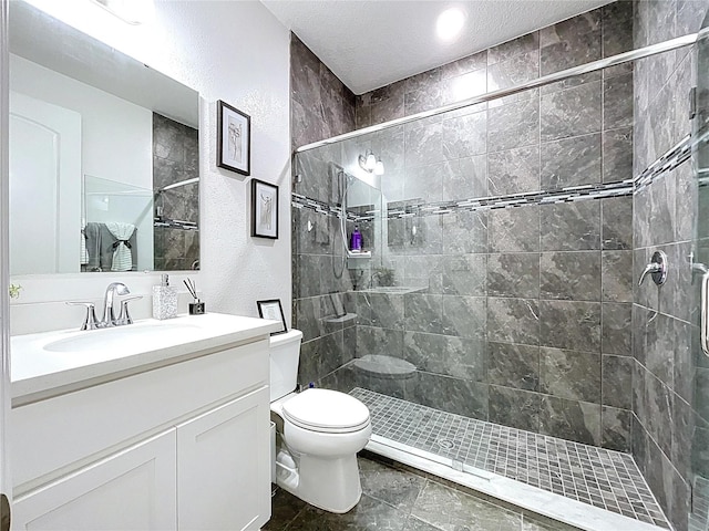 bathroom featuring tiled shower, a textured wall, vanity, and toilet