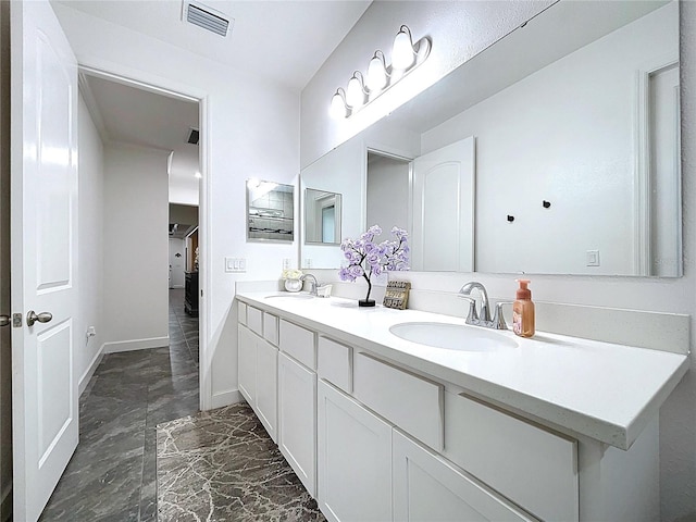 bathroom with visible vents, a sink, baseboards, and double vanity