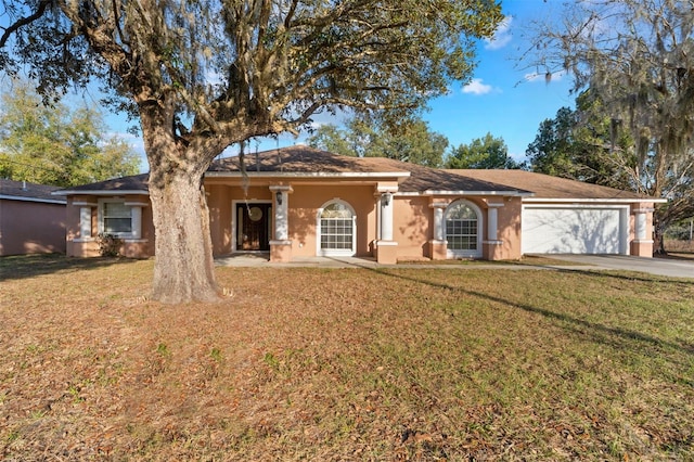 view of front of property featuring a garage, driveway, a front lawn, and stucco siding