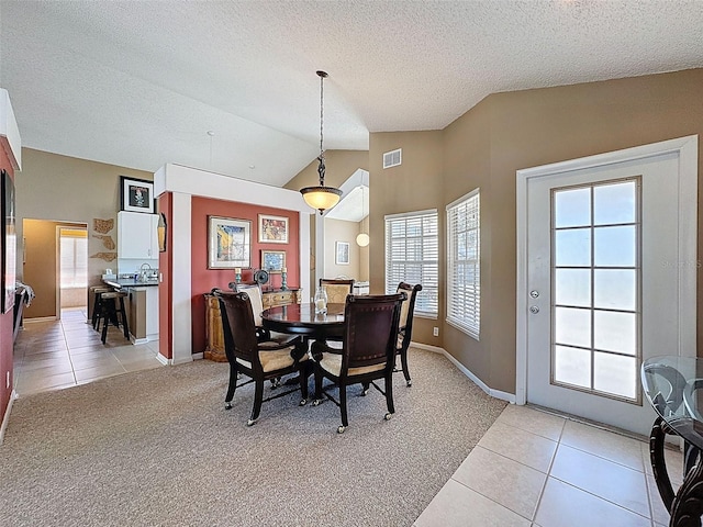 dining space with light tile patterned floors, visible vents, lofted ceiling, and light colored carpet