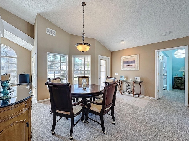 dining space featuring visible vents, baseboards, lofted ceiling, light carpet, and a textured ceiling