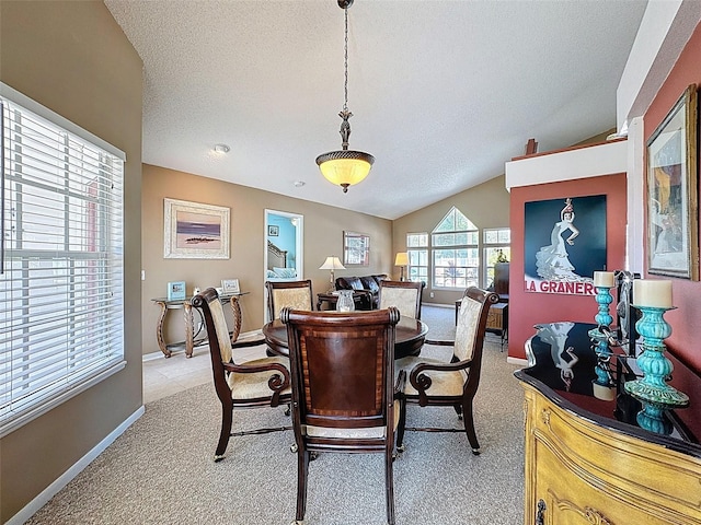 dining space featuring a textured ceiling, vaulted ceiling, baseboards, and light carpet