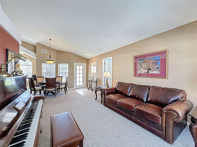 living area featuring visible vents, plenty of natural light, carpet flooring, and vaulted ceiling