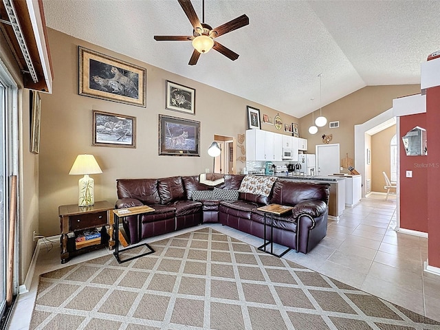 living room with visible vents, ceiling fan, vaulted ceiling, light tile patterned floors, and a textured ceiling