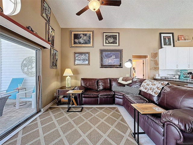 living area with a ceiling fan, baseboards, vaulted ceiling, a textured ceiling, and light colored carpet