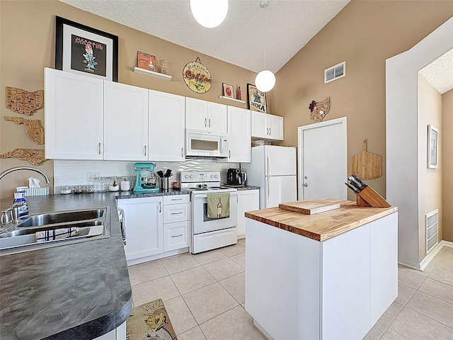 kitchen with a sink, white appliances, white cabinets, and light tile patterned floors