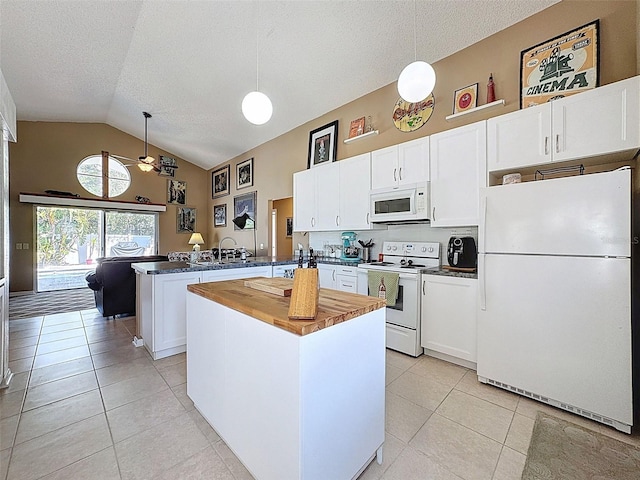 kitchen featuring a sink, white appliances, a peninsula, light tile patterned flooring, and hanging light fixtures