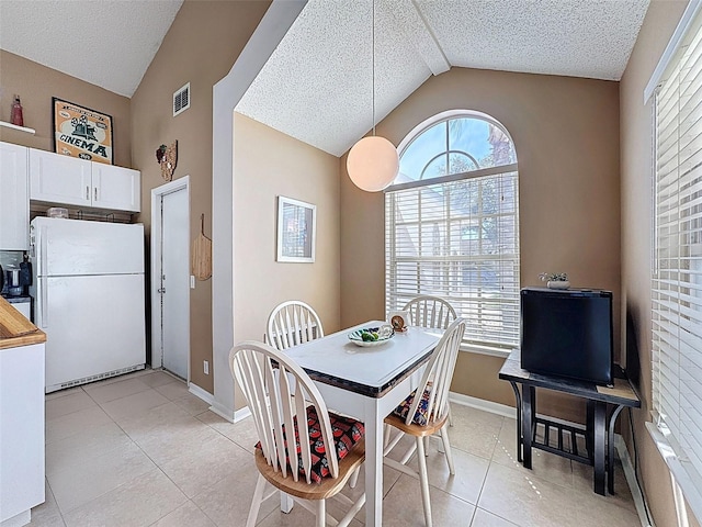 dining area featuring vaulted ceiling, visible vents, and a textured ceiling