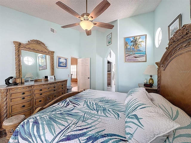 bedroom with visible vents, arched walkways, ceiling fan, ensuite bathroom, and a textured ceiling