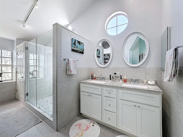 full bath with tile patterned floors, a stall shower, tile walls, and a sink