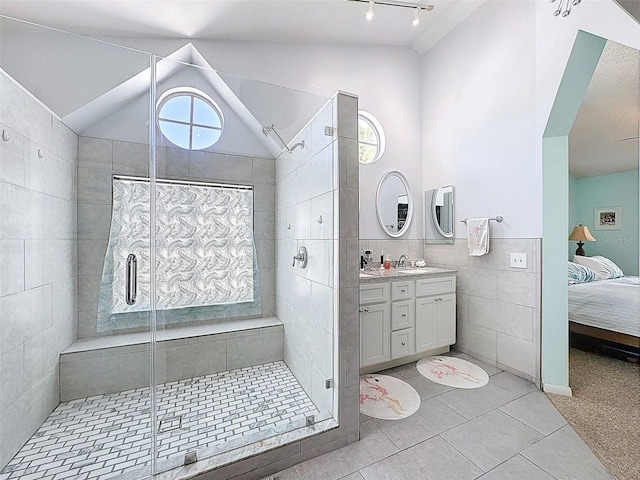 bathroom featuring tile walls, lofted ceiling, a stall shower, ensuite bathroom, and vanity