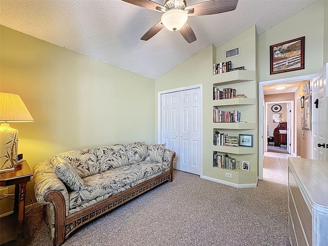 living area featuring visible vents, lofted ceiling, ceiling fan, a textured ceiling, and carpet flooring