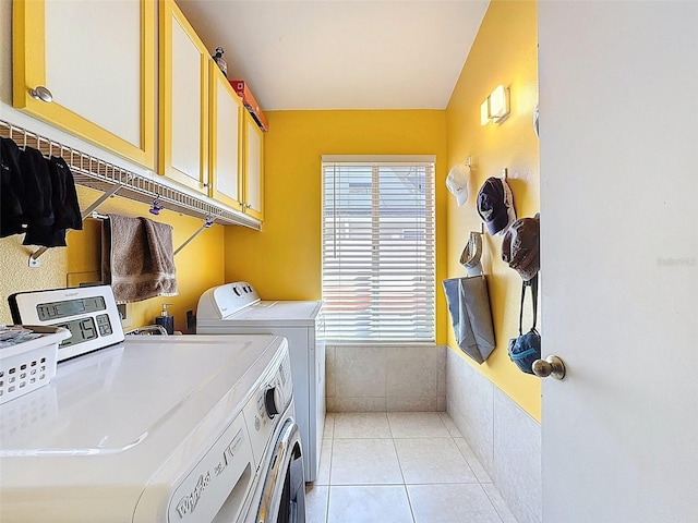 washroom with cabinet space, light tile patterned floors, and washing machine and dryer